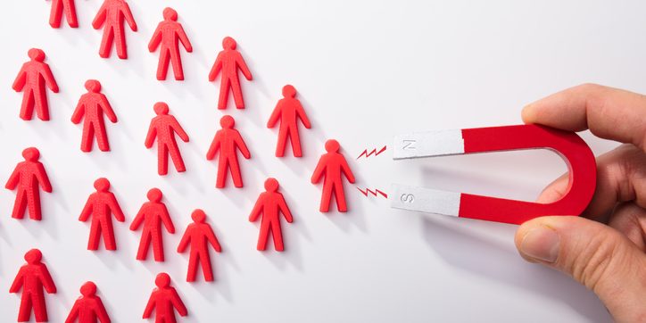 Human Hand Attracting Human Figures With Horseshoe Magnet